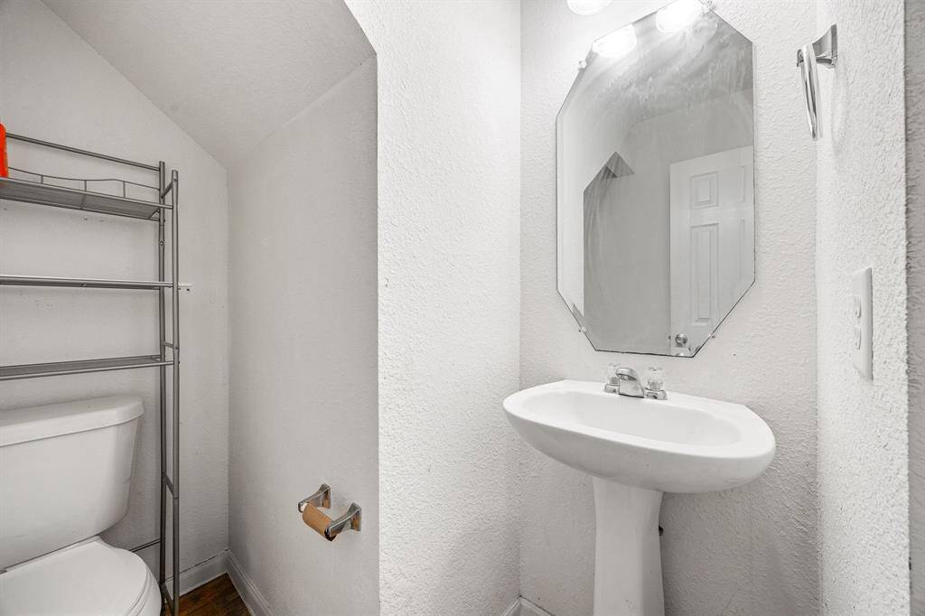 Charming half bath with a classic pedestal sink,  mirror, and easy-care finishes, perfect for guests and daily use.