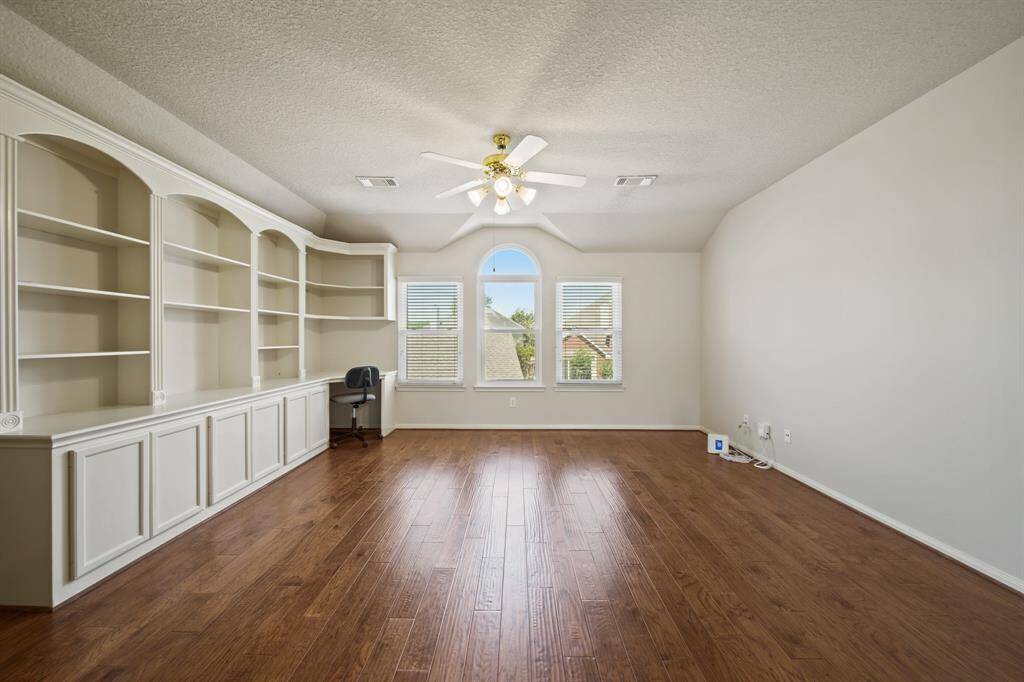 Upstairs game room with beautiful hardwood flooring & built in storage.