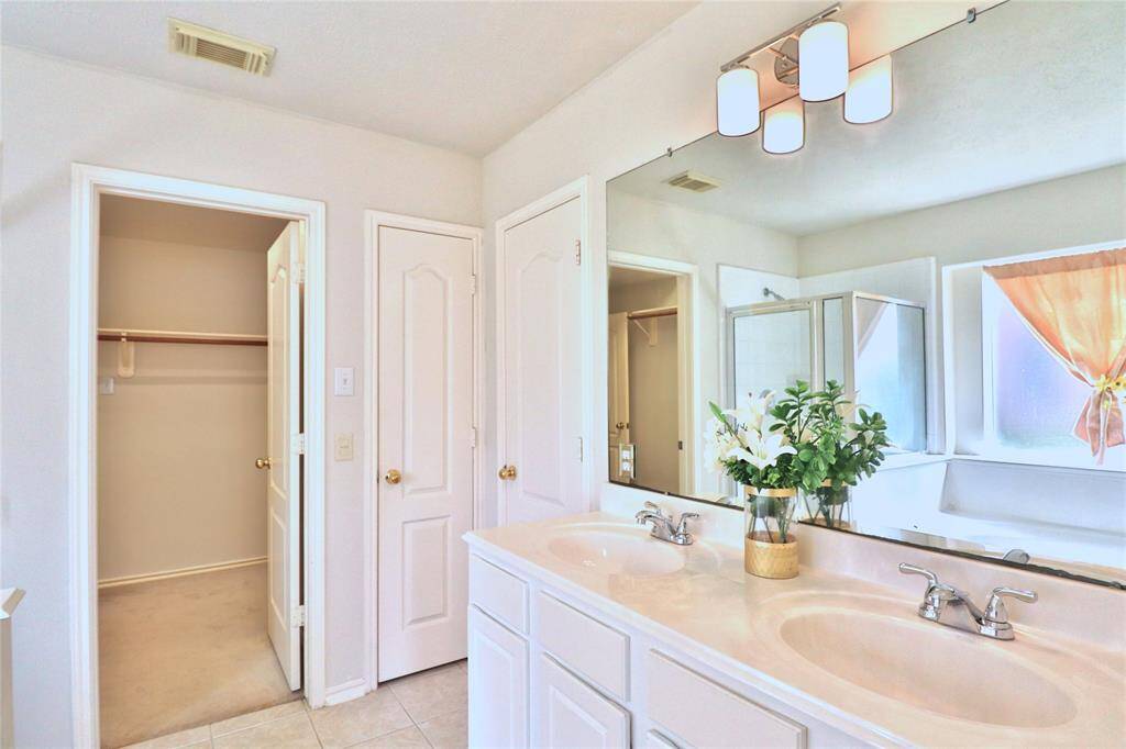 primary bathroom with dual sinks, a large mirror, and modern lighting.