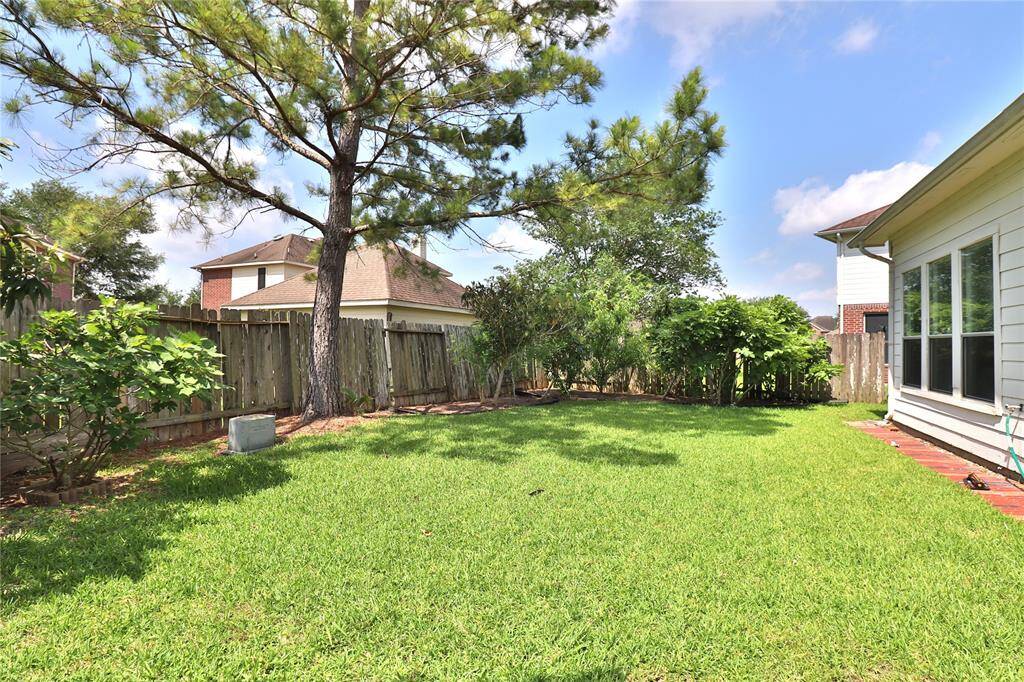 A spacious backyard with lush green grass, mature trees,  Perfect for outdoor activities or relaxation.