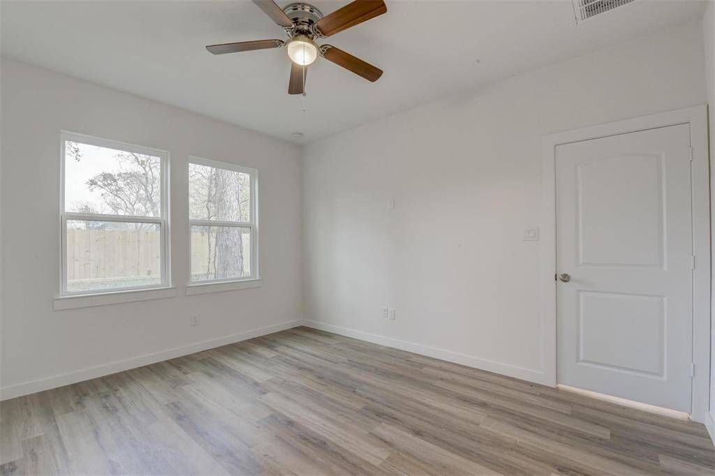 Bright and inviting room with large windows, a ceiling fan, and chic vinyl wood flooring—perfect for a cozy bedroom or office.