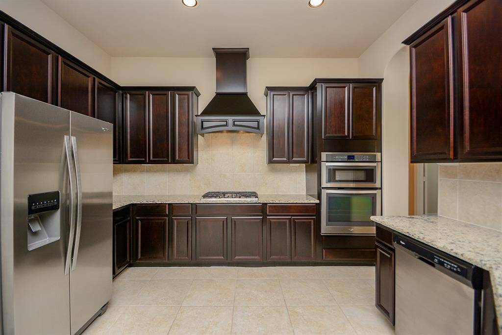 Just wow! This spectacular kitchen is a piece of art in itself! Rich, shiny, chocolate colored cabinetry complements the pale floor tile. Stainless steel appliances are flanked by tons of storage and unobstructed areas for prep, cooking and serving.