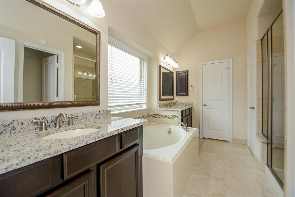Sweet sophistication defines your primary ensuite bath! The appealing light/dark theme of the home prevails here, too, in cabinetry, flooring and soothing walls. The lovely garden tub faces the walk-in glass enclosed shower. You have relaxing options. His/her sinks are placed on either side of the tile-surrounded bathtub.
