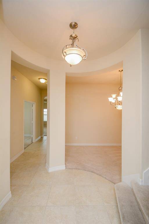 Wide open, yet connecting areas of this home are perfect examples of the joy of the open floor plan! Peeking out at the bottom right of this photo, is the home's lovely carpeted staircase to the 2nd story. Note the exquisite carved wall detail and muted neutral shades on the vast walls!
