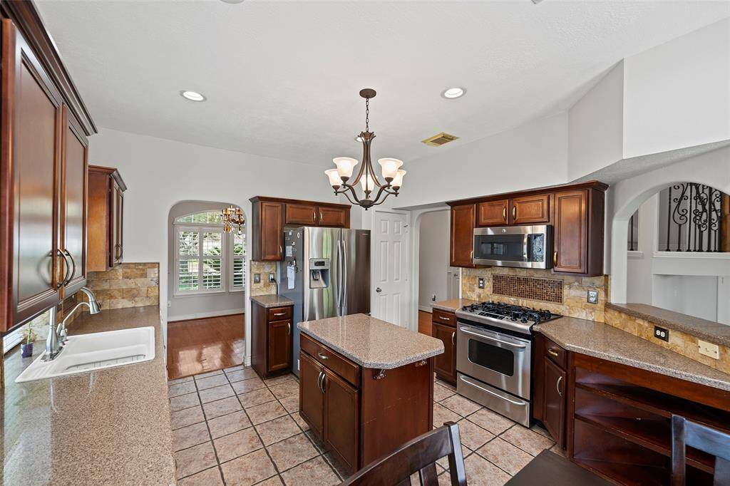 This large kitchen provides ample counter space, stainless steel appliances, and a convenient island for food prep.