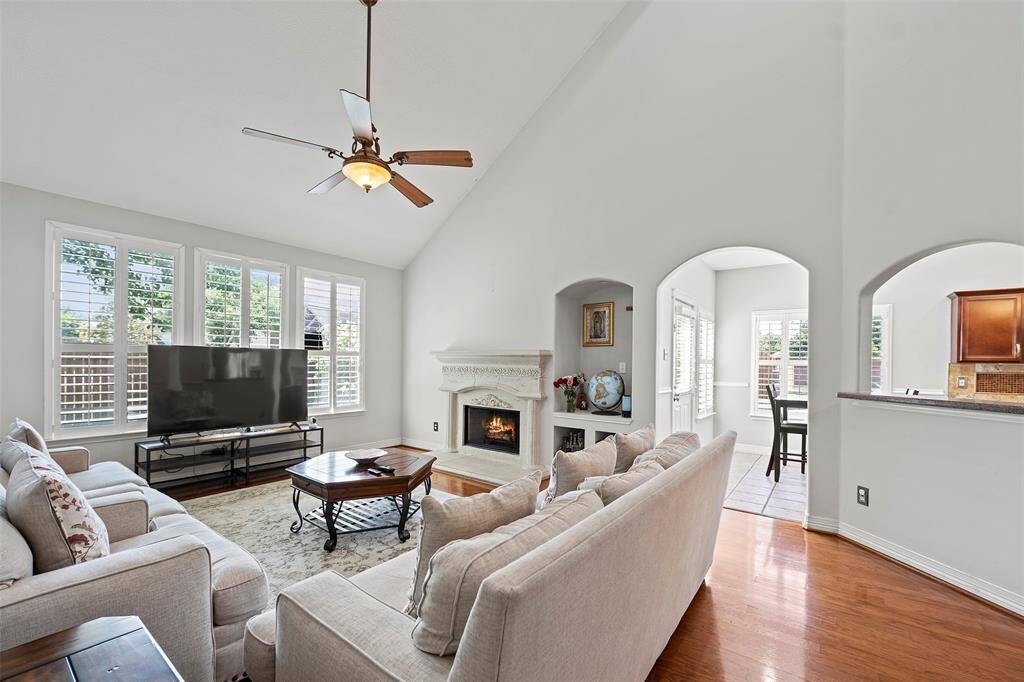 This spacious living room provides a high ceiling, fireplace, and ample windows to provide natural lighting throughout.