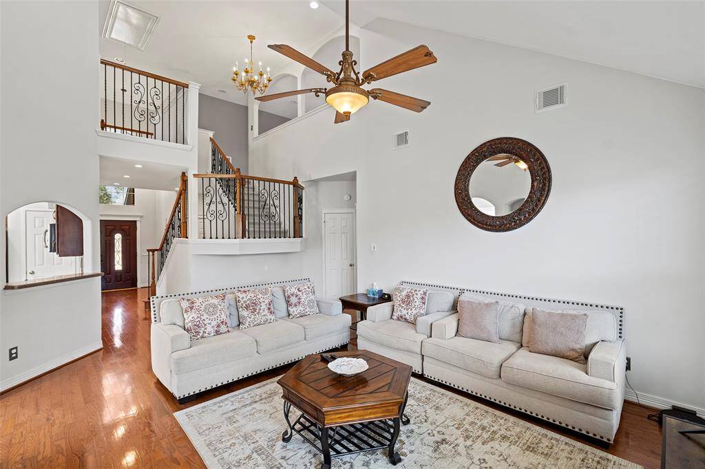 This angle of the living room shows the wood flooring throughout and wrought iron stair railings.