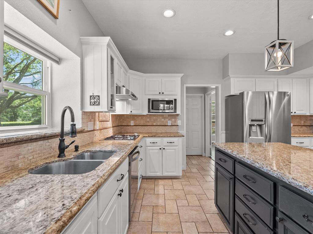 This kitchen features elegant granite countertops, a large center island with dark cabinetry, and stainless steel appliances.