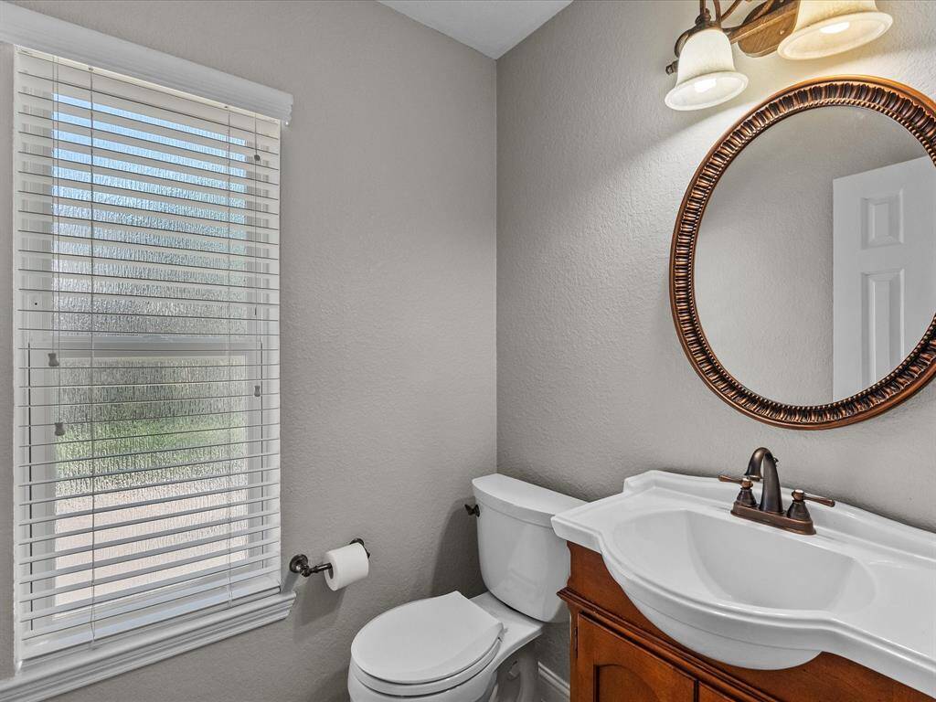This bathroom features a modern design with neutral walls, a white toilet, and a stylish wooden vanity with a white sink.