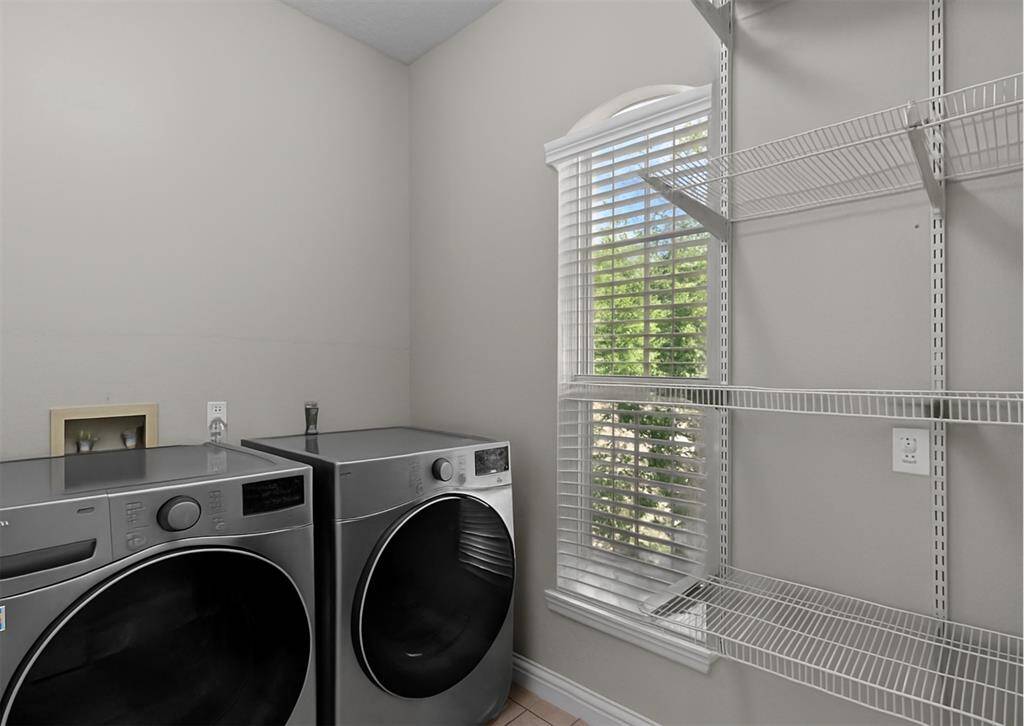This photo showcases a full size laundry room with plenty of natural light and shelving for storage.