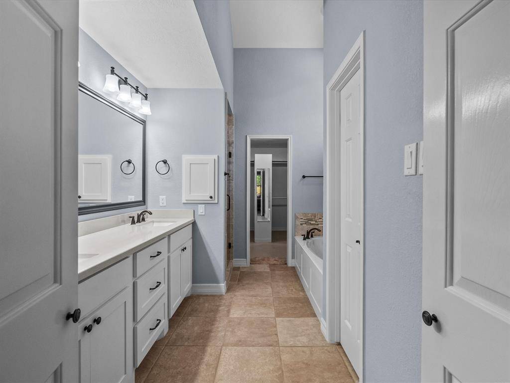 This bathroom features a dual-sink vanity with ample storage, a large mirror, and modern light fixtures.