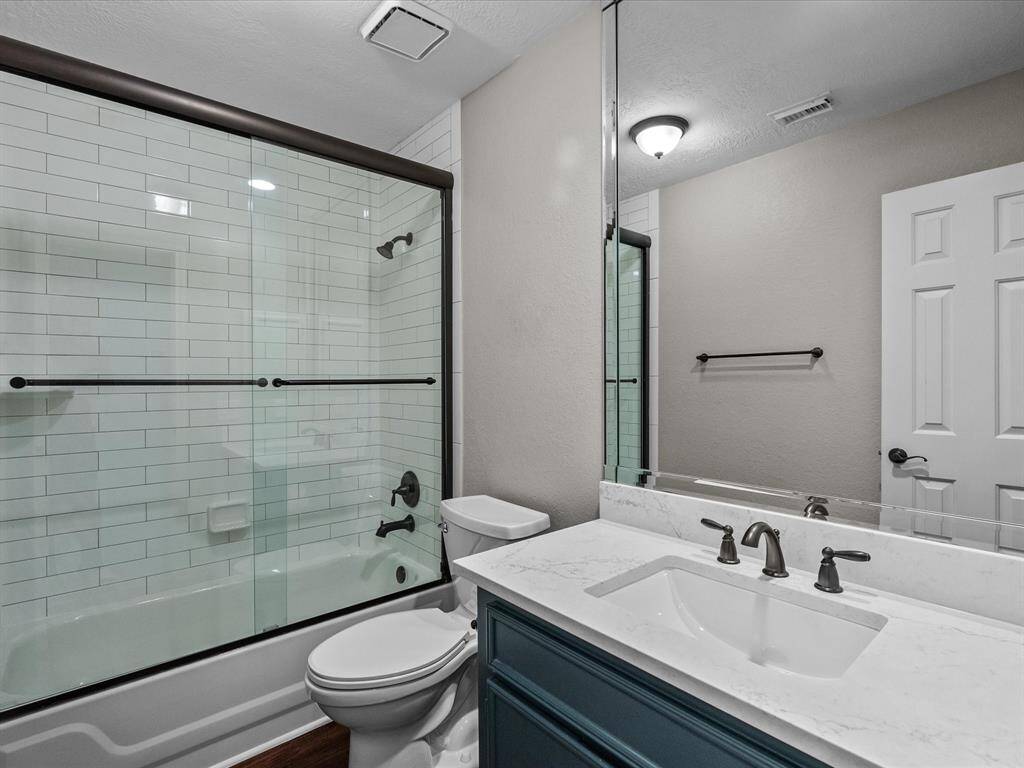 This bathroom features a clean, modern design with a white subway-tiled shower and glass doors.
