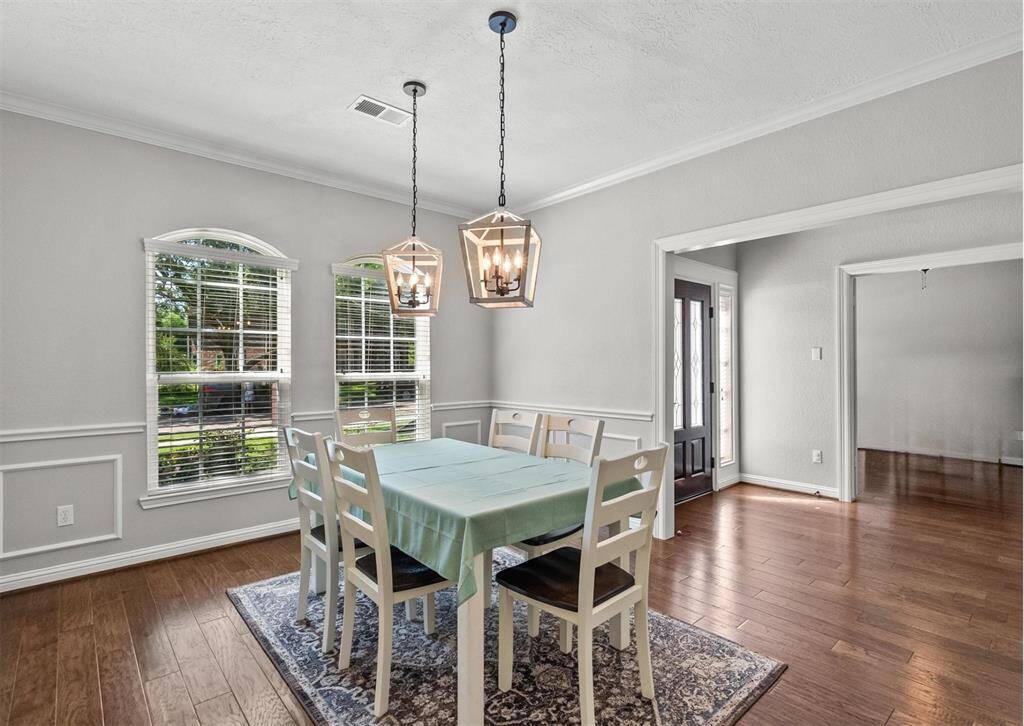 Beautiful dining room with rich hardwood floors, light fixtures, and abundant natural light from windows.