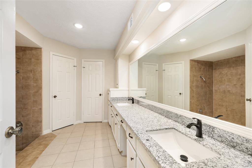 he en-suite bathroom enhances the space with its thoughtful design, featuring a step-down, spacious walk-in shower, dual sinks, and vanity space for added convenience.