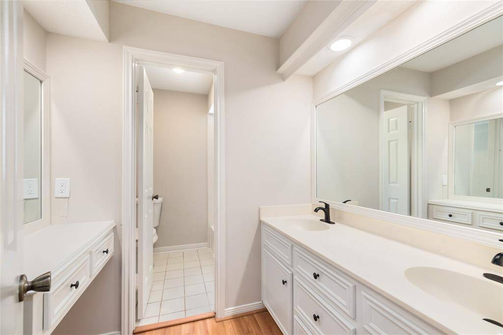 This well-appointed secondary bathroom features a spacious vanity area with dual sinks, conveniently separated from the bath and toilet for added privacy and functionality. New water faucets, installed throughout the house, enhance the bathroom’s modern appeal while offering improved efficiency.