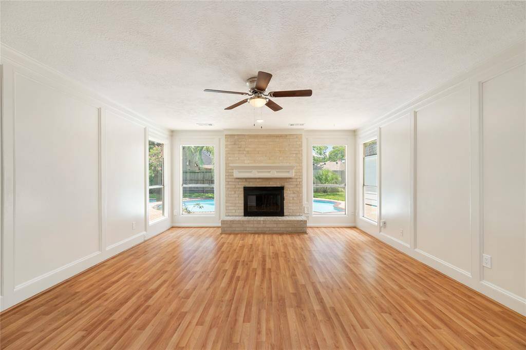 This inviting living space blends character and comfort with board and batten wall detailing and a charming brick fireplace crowned by a classic mantle. Large windows offer peek views of the backyard oasis, bringing in natural light and a tranquil connection to the outdoors.