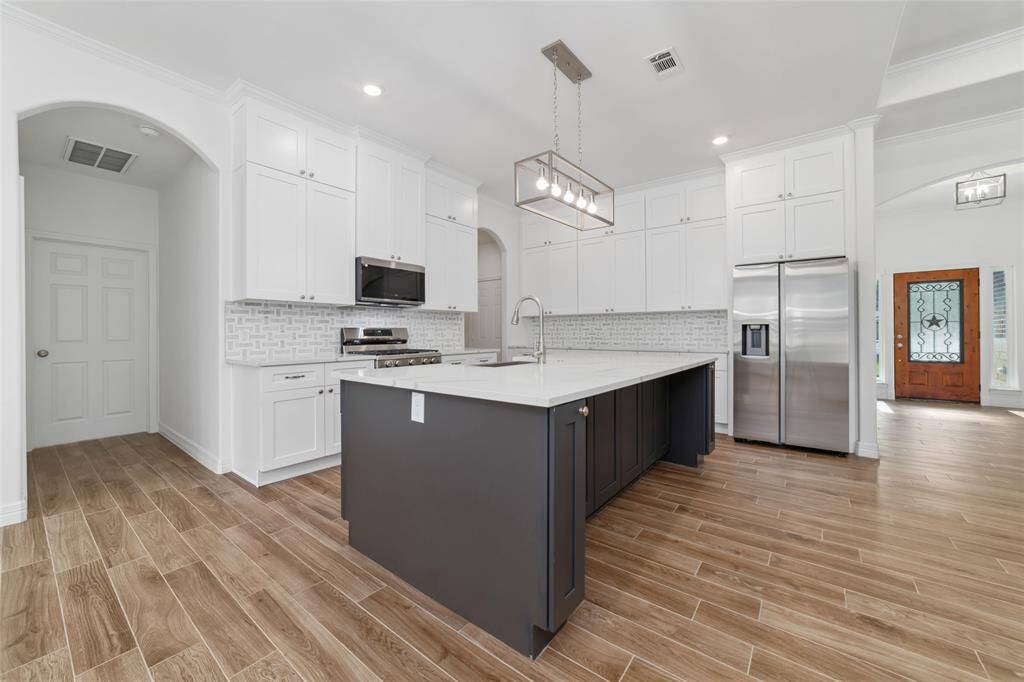 Dark gray center island is a beautiful contrast against the light and bright kitchen with space for family and friends to cook together.