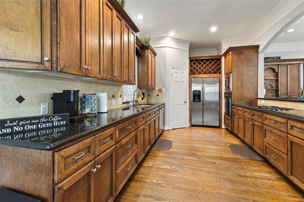 This spacious kitchen features elegantwooden cabinetry, granite countertops,and stainless steel appliances. Itincludes a built-in wine rack, amplestorage, and a hardwood floor, creatinga warm and inviting atmosphere perfectfor cooking and entertaining.