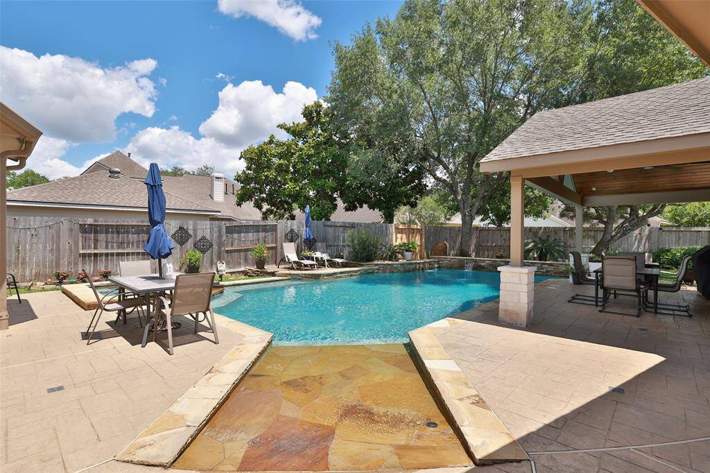 Large backyard is an entertainer's delight with a sparkling pool, hot tub and covered patio.