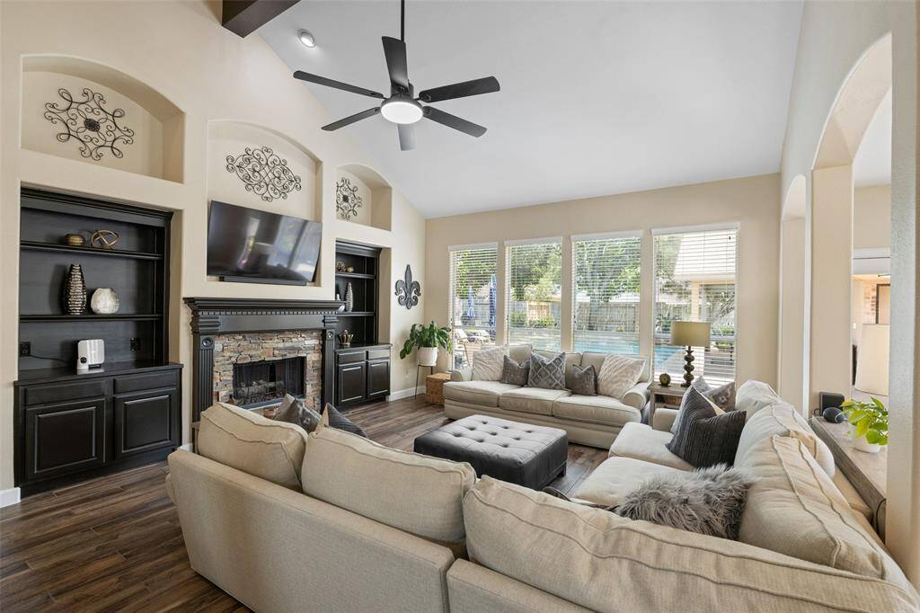 Living room features a fireplace with ceramic logs, built-in cabinets, new ceiling fan and overlooks the gorgeous view of the pool.