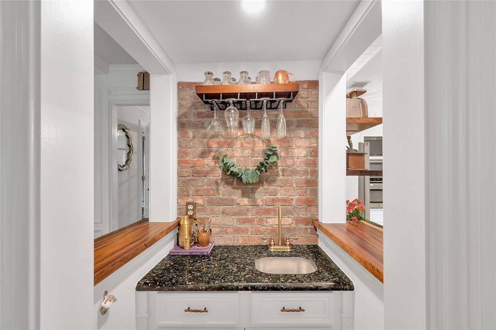 This cozy nook features a charming wet bar with a rustic brick backsplash, elegant granite countertop, and wooden shelves for glassware. Perfect for entertaining in style.