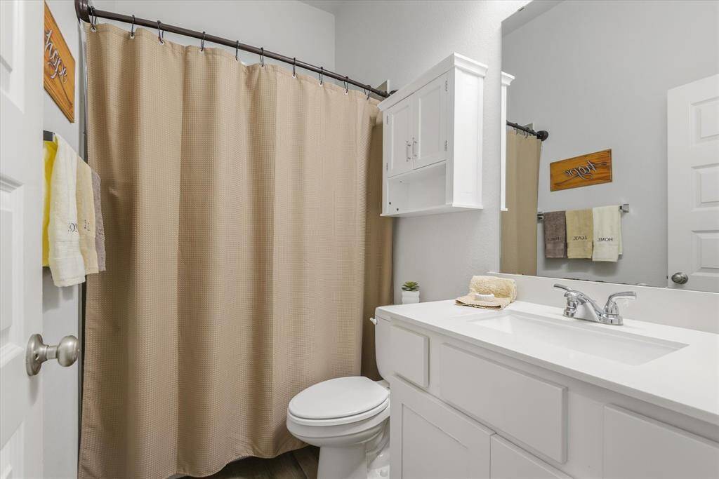 This bathroom features a clean, modern design with a white vanity and sink, a neutral-toned shower curtain, and storage options including a wall-mounted cabinet. It has a fresh and inviting look, perfect for a home buyer.