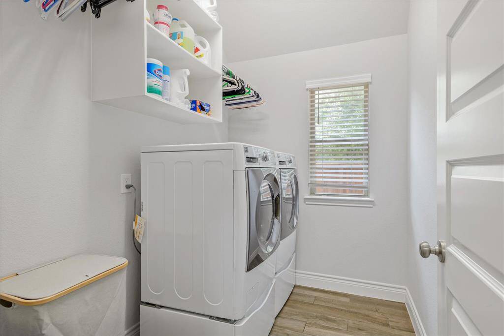 This is a bright and functional laundry room with modern appliances, shelving for storage, and a window for natural light.