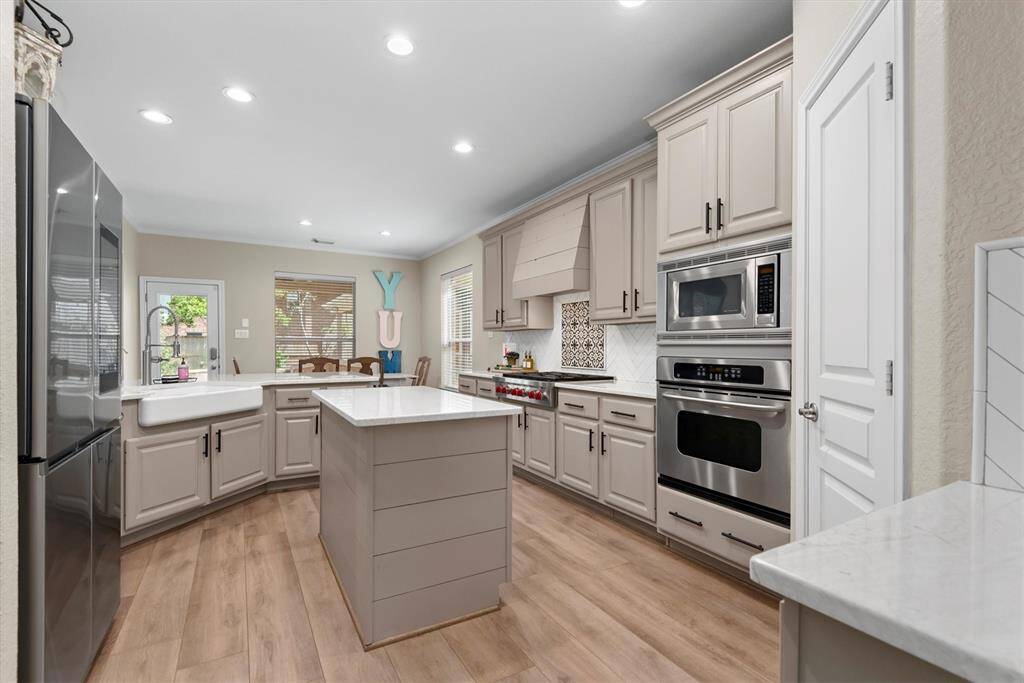 Modern kitchen with beautiful cabinetry, sleek Cambria Quartz counters, designer backsplash, stainless steel appliances, central island and a farmhouse sink. Perfect for the family chef!