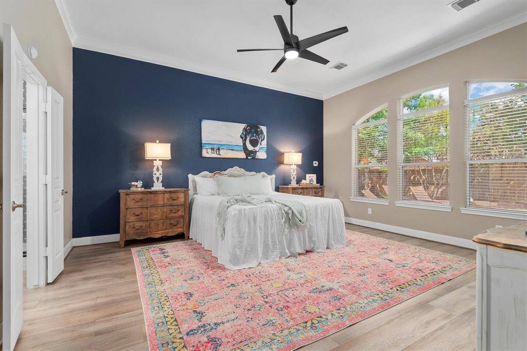 The spacious primary bedroom offers a serene retreat, featuring a bold navy accent wall that adds a modern touch and depth to the space. Large picture windows fill the room with natural light and provide peaceful views of the backyard.