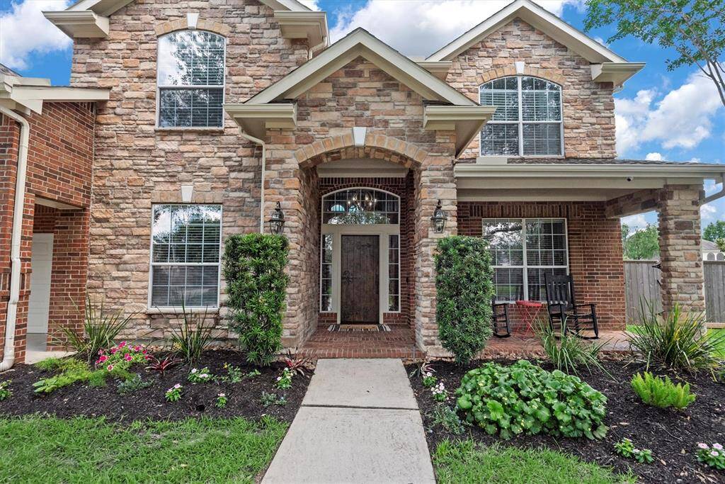 The entrance is framed by elegant columns and greenery, creating an inviting curb appeal.