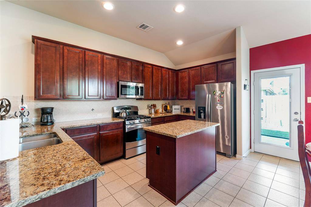 Bright and spacious kitchen with ample counter space, a large island, and plenty of room for a dining table, whether large or small, plus a brand-new microwave and 2021 Whirlpool fridge that stay with the home.