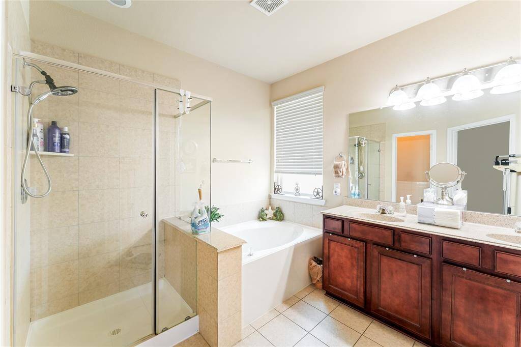 Bright and sizable primary bedroom, easily fitting a king-sized bed with plenty of additional room, leading into an en-suite bath featuring a glass-enclosed shower, garden tub, double vanity, walk-in closet, and private toilet room.