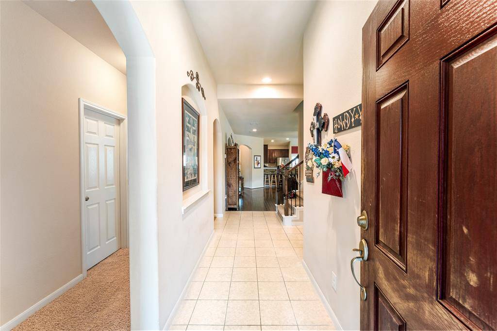 Welcoming entryway with a spacious layout—hall to the left leads to two bedrooms and a full bath, while the hall to the right offers access to the garage and laundry; straight ahead opens to the main living, dining, and upstairs bonus room.