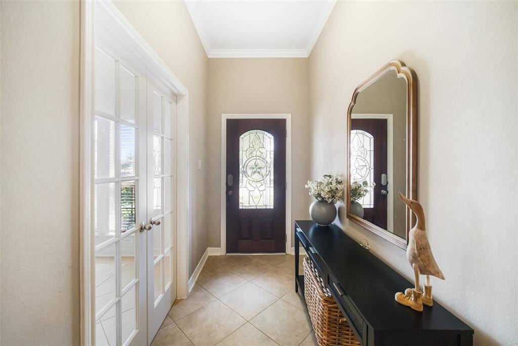 The light and bright foyer is beautifully accented by the home's lead glass front door, crown molding, and large tile floor laid on the diagonal.