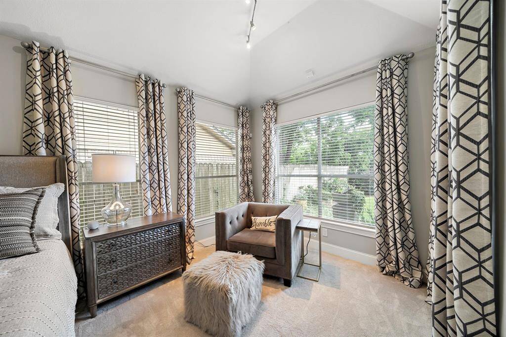Bright and cozy bedroom corner with large windows, patterned curtains, modern furniture, and a garden view. Ideal for relaxation and natural light.