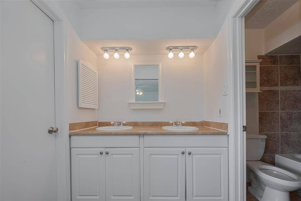 Primary bathroom offers double vanity and updated light fixtures.