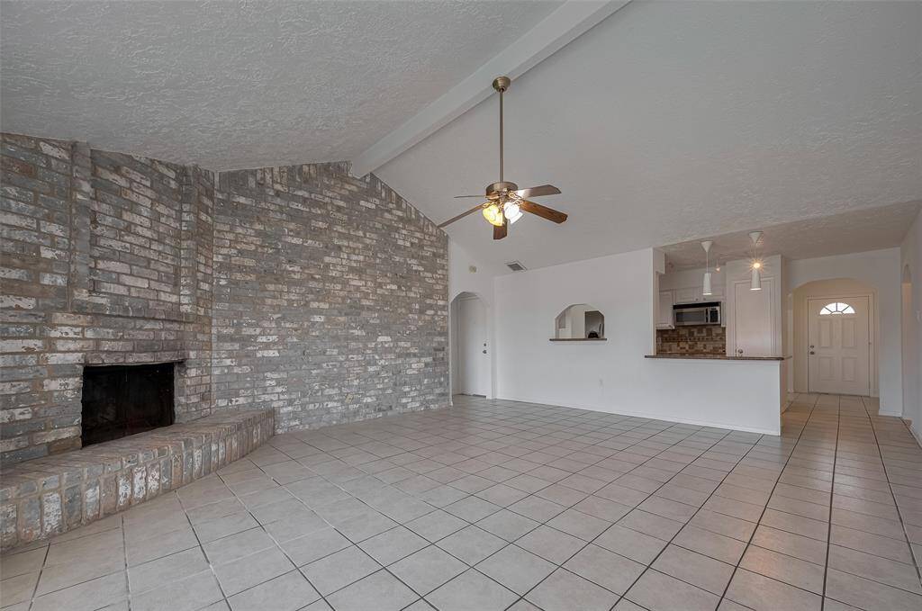 View of living room area with high ceilings and wood burning fireplace.