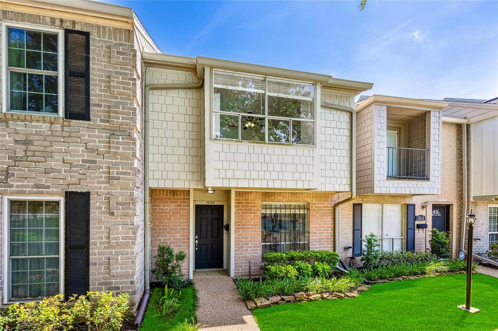 This charming townhouse features a classic brick exterior with a modern touch. It has large windows for natural light and a well-maintained front yard. The entrance is welcoming, leading to a cozy and inviting home.