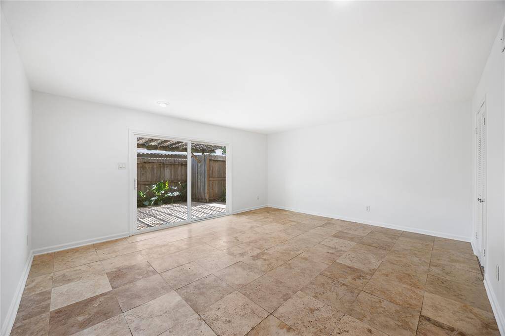 This bright living room features a modern, neutral design with large sliding glass doors that lead to a cozy outdoor space, enhancing natural light.