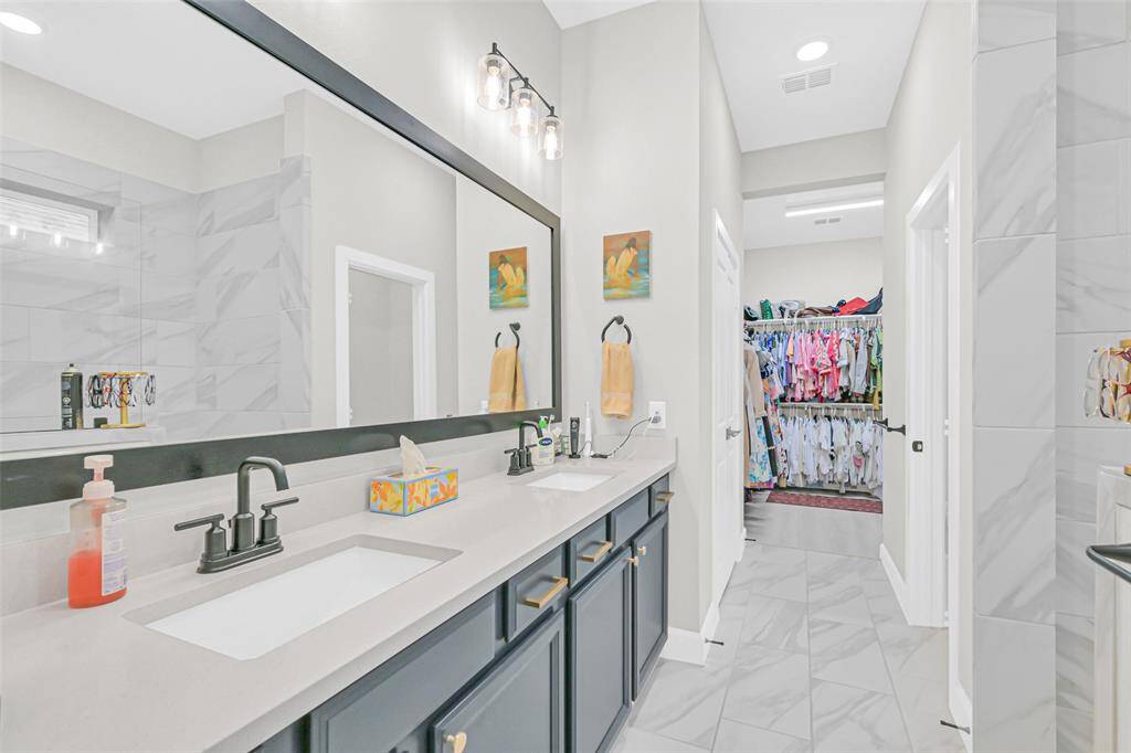 Double vanities with quartz countertops and striking matte black fixtures provide style and function, complemented by custom lighting and a large framed mirror.
