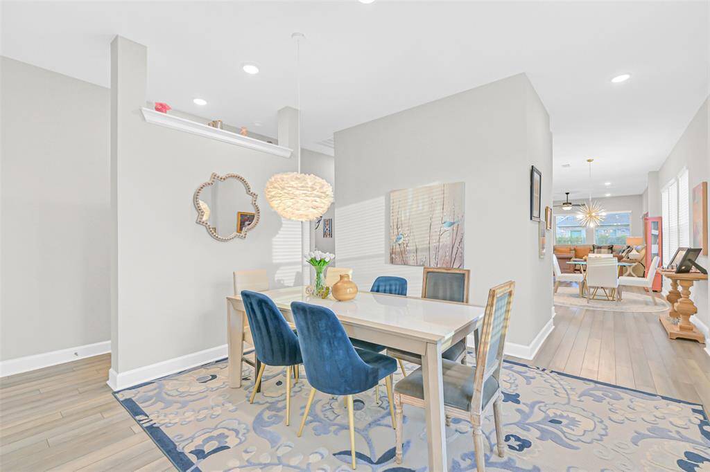 The floor plan begins with the sophisticated dining room, anchored by a stunning modern pendant light. A neutral color scheme and recessed lighting are conducive to conforming to many different styles.