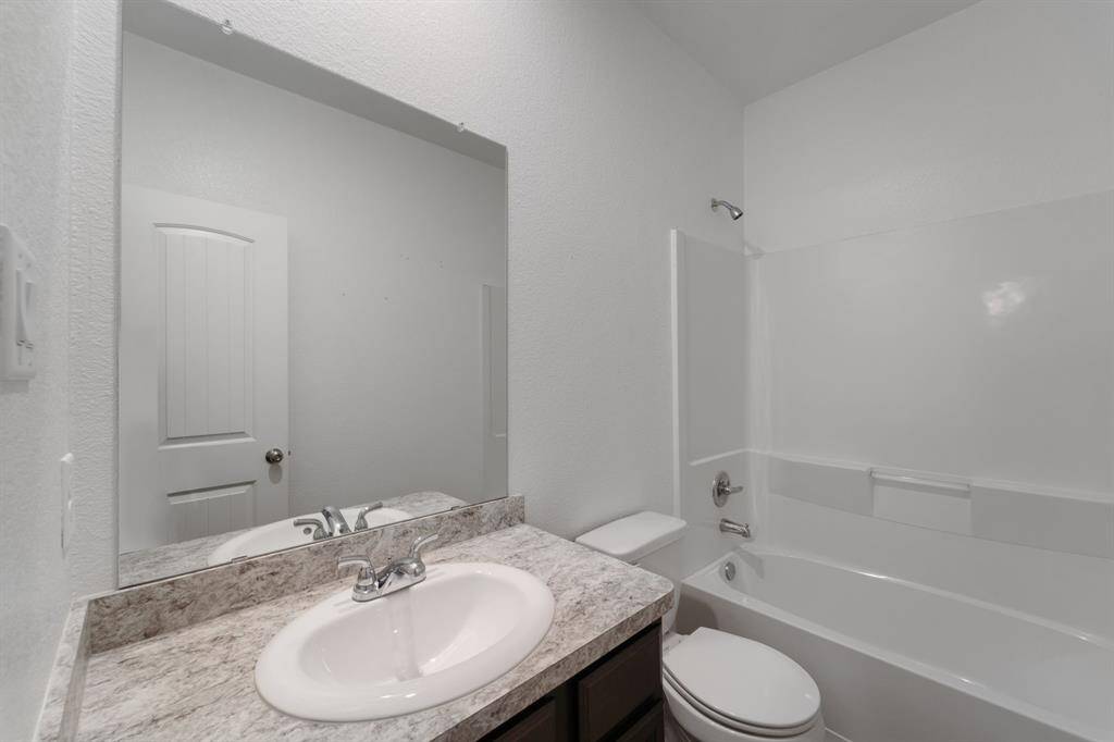 Secondary bathroom with granite countertops and backsplash, and a shower/tub combo.
