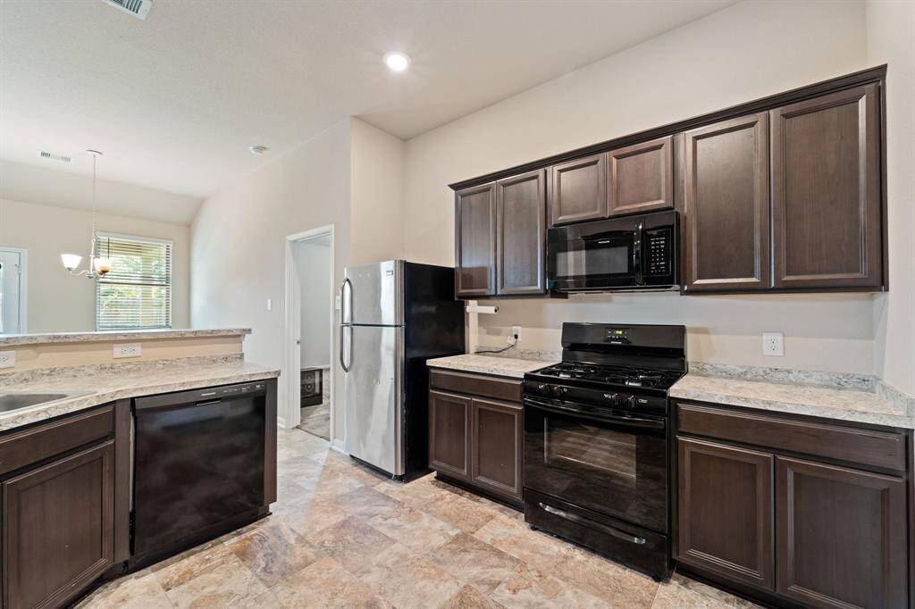 The kitchen features stainless steel appliances, recessed lighting, and tile floors.