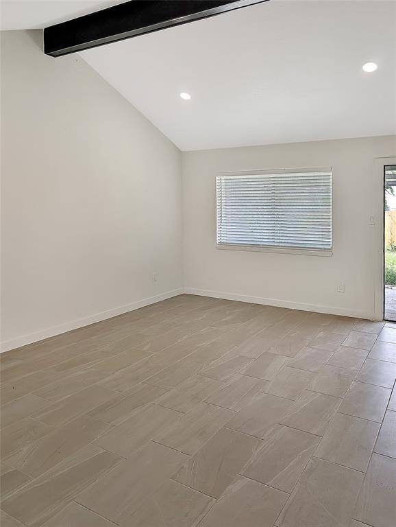 This bathroom features a sleek, modern design with a white vanity, black fixtures, and a unique octagonal window. It has a clean, minimalist look with neutral tile flooring.