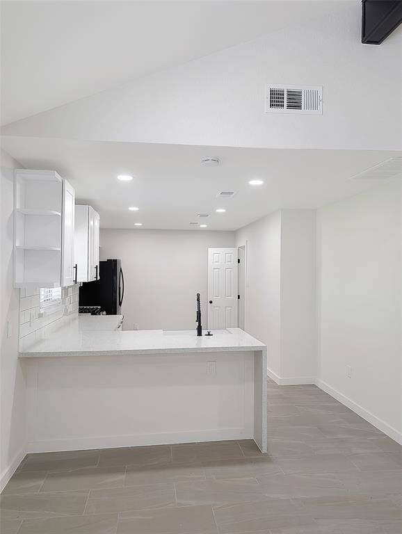 This modern bathroom features a sleek white vanity with a quartz countertop and black fixtures. It includes a rectangular mirror, a bathtub with a rainfall showerhead, and stylish marble-patterned tiles, creating a clean and contemporary look.