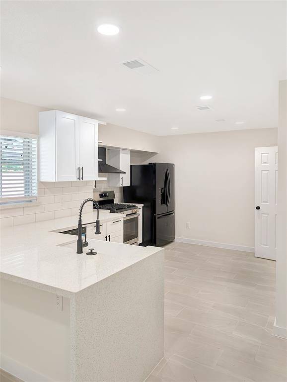 This photo shows a small closet with a white door, featuring a single hanging rod. The room has light-colored walls and tiled flooring, offering a clean and modern look.