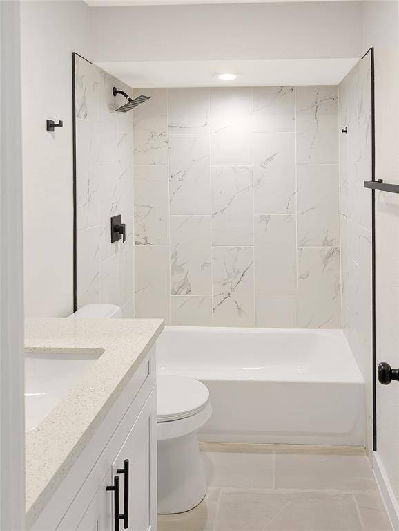 Modern kitchen with white cabinetry and a sleek black refrigerator. Features a gas range, stylish faucet, and neutral tile flooring. Bright and inviting with recessed lighting.