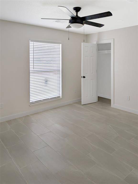 This photo shows a small, bright pantry or storage closet with neatly fitted shelves, a white door, light-colored tile flooring, and neutral walls, offering a clean and functional space.