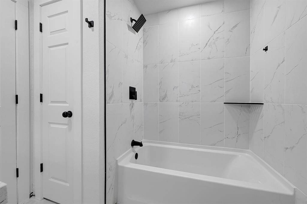 This is a clean, white closet with a wooden rod and two shelves, providing ample space for hanging clothes and storage.