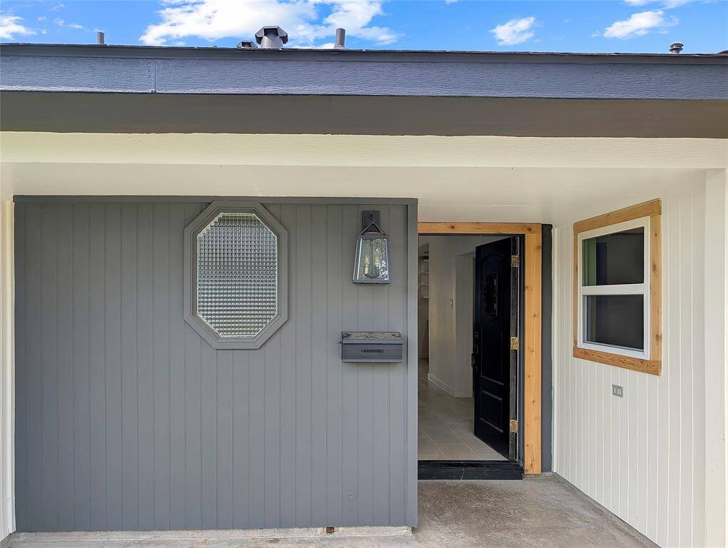 This photo shows a bright, welcoming entryway with neutral walls, tiled flooring, and a decorative front door. It leads to a space with a window and a door opening to the backyard, providing natural light.